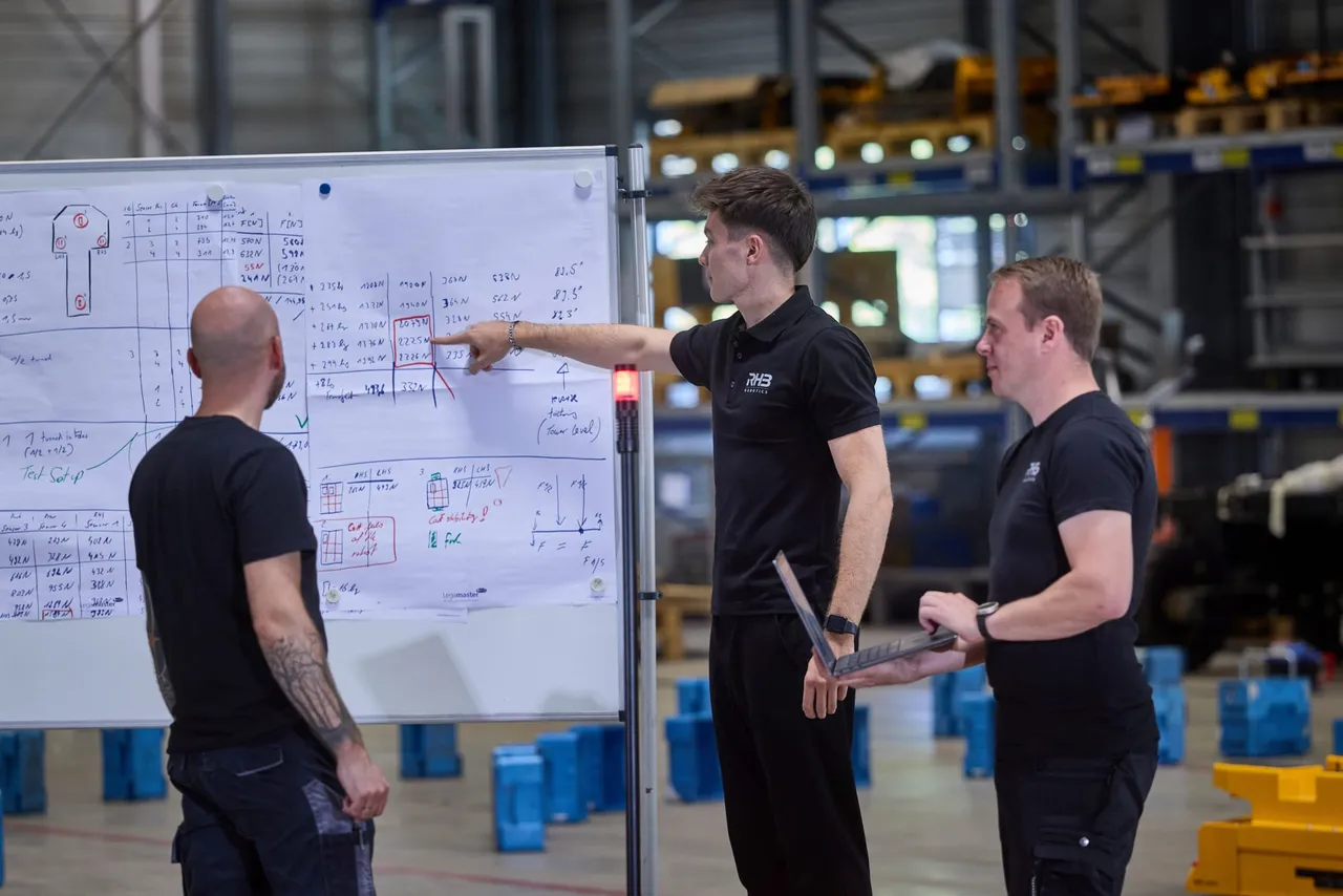Drei Servicetechniker besprechen Messwerte am Whiteboard in der Halle