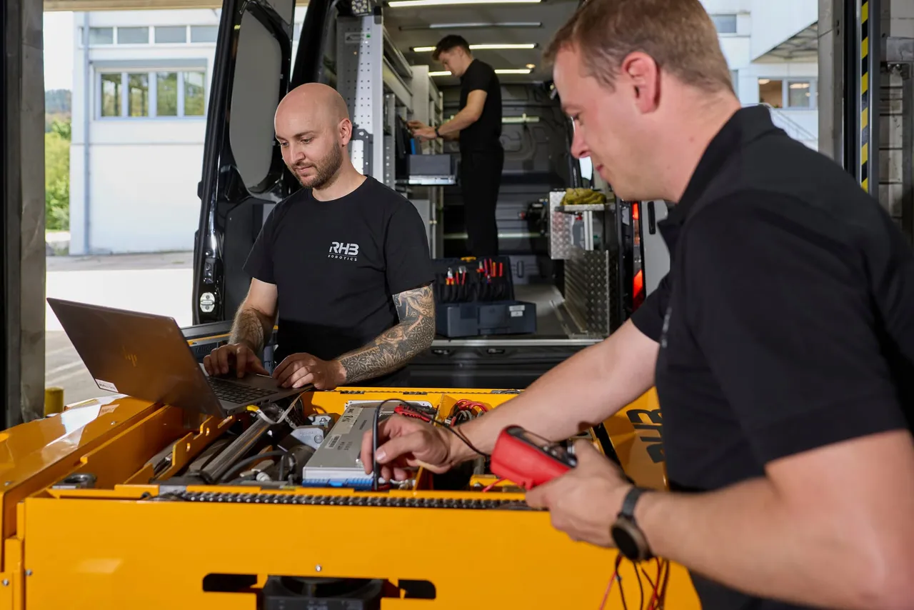 Wartung am geöffneten AMR, Servicetechniker mit Laptop und Messgerät am Servicefahrzeug